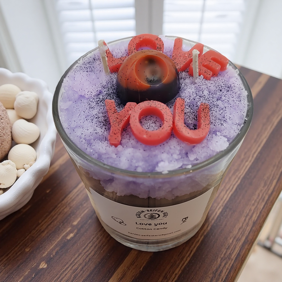 Nahaufnahme der Zuckerwatte-Duftkerze mit „Love you“-Buchstaben und runder Wachsdekoration