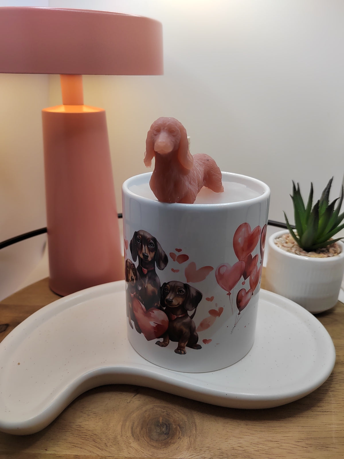 Dackel-Kerze in weißer Tasse mit roter Wachsfigur und Hundemotiv von vorn