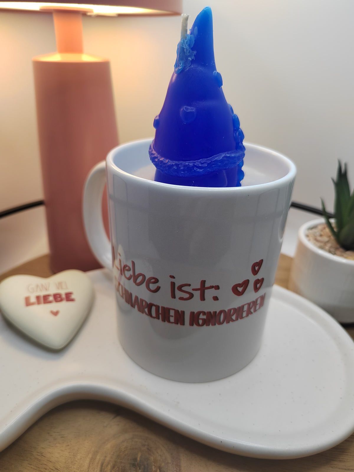 Nahaufnahme der Kerze mit blauem Wichtel in Rückansicht und Spruchseite der Tasse