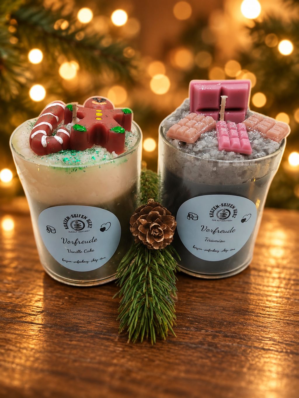 Zwei Weihnachtskerzen im Glas „Vorfreude“ mit den Duftvarianten Vanille Cake und Tiramisu vor warmem goldenem Lichterhintergrund