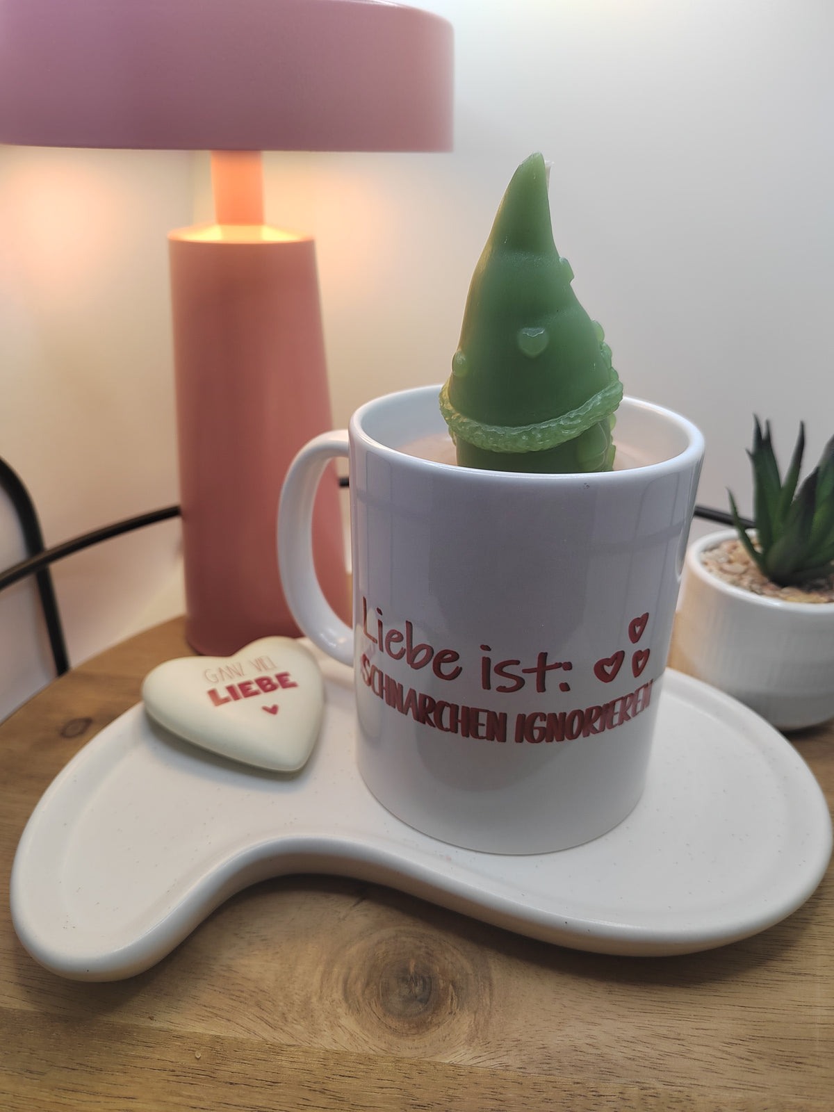 Kerze in weißer Keramiktasse mit grünem Wichtel und Spruch „Liebe ist: Schnarchen ignorieren“