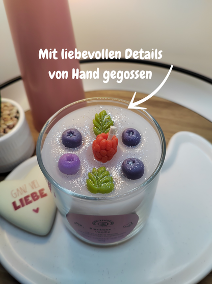 Nahaufnahme der handgegossenen Blaubeer-Vanille-Duftkerze mit Beeren- und Blatt-Dekoration